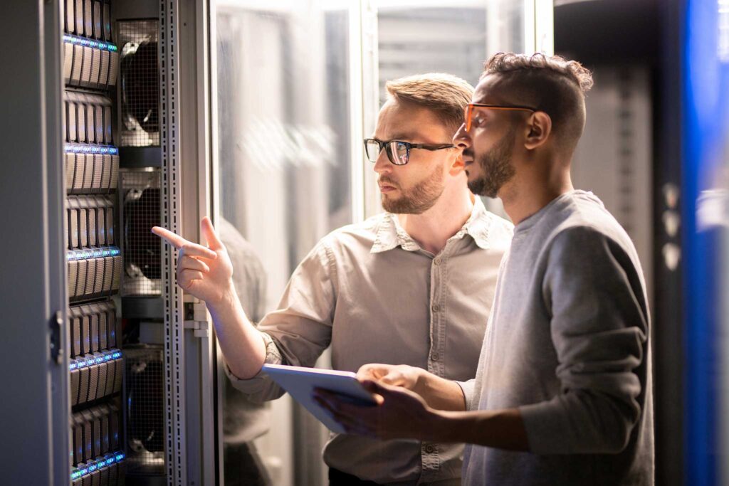 Two engineers reviewing server equipment in a server room