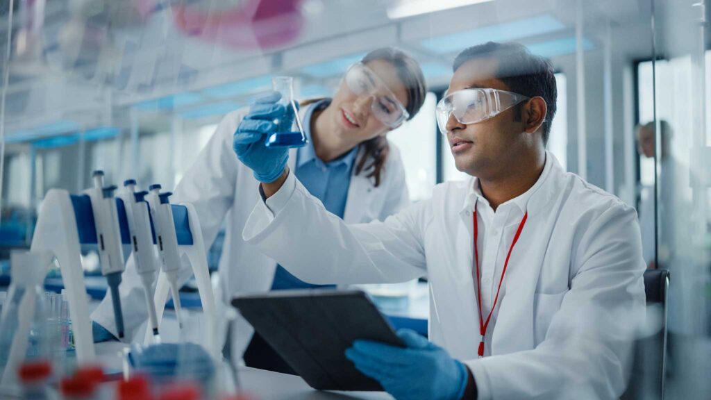 Two researchers in lab coats examining a sample in a biotechnology laboratory